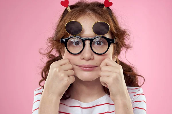 Fille gaie avec des lunettes de soleil pigtails rayé t-shirt style de vie fond rose — Photo