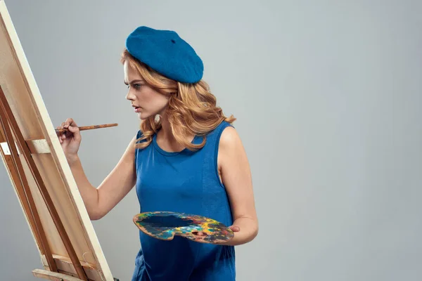 Donna artista blu basco tavolozza disegno su cavalletto arte creatività luce sfondo — Foto Stock
