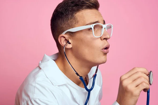 Jeune médecin avec un stéthoscope et des lunettes sur fond rose infirmière stagiaire modèle — Photo