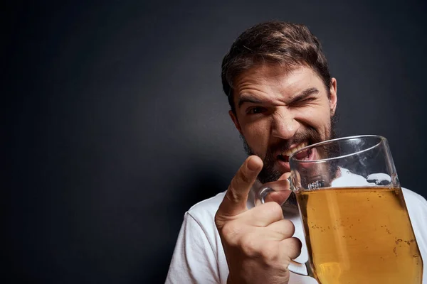 Beyaz tişörtlü, bir kupa birası olan bir adam. Duyguları olan, koyu tenha bir arka planda sarhoş bir adam. — Stok fotoğraf