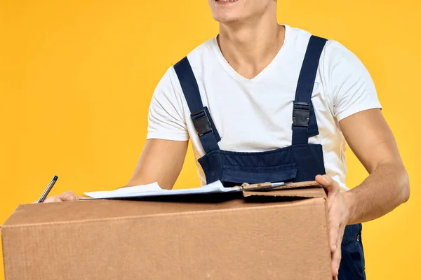 Werkman in uniform met box hand levering laadservice gele achtergrond — Stockfoto