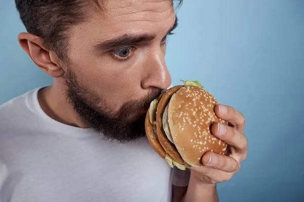 Emocionální člověk hamburger fast food strava jídlo close-up modré pozadí — Stock fotografie