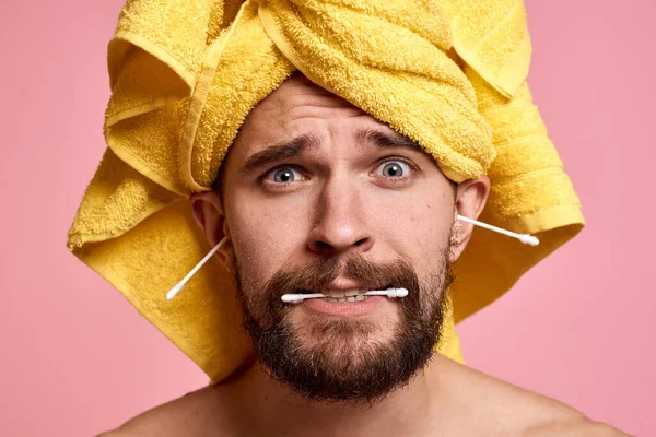 Man met gele handdoek op zijn hoofd spons schone huid zorg roze achtergrond — Stockfoto