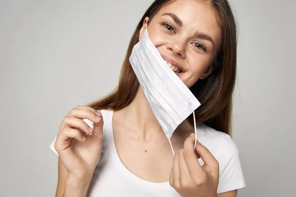 Mujer poniéndose la cara máscara médica sonrisa camiseta blanca estilo de vida — Foto de Stock