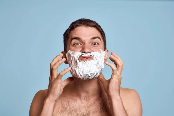 Man met scheermes en wit schuim op zijn gezicht blauwe achtergrond naakt romp baden procedures — Stockfoto