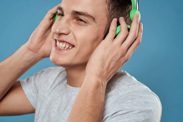 Férfi zöld fülhallgató zenét hallgat szórakoztató életmód fehér póló kék háttér — Stock Fotó