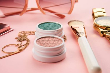 Göz falı aksesuarlar, boncuklar makyaj fırçaları pembe arka planda profesyonel kozmetik ürünleri koleksiyonu.