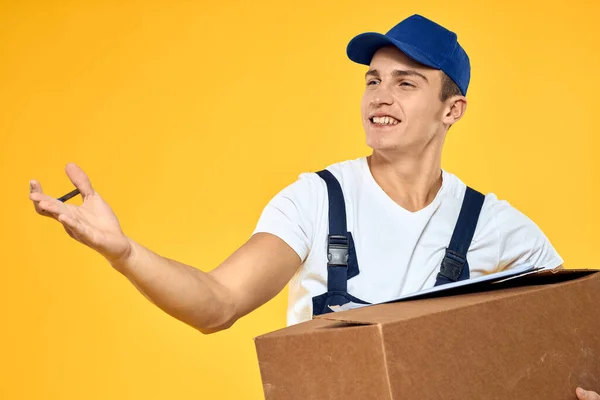 Arbeiter in Uniform mit Box Hand Lieferservice Verladedienst gelben Hintergrund — Stockfoto