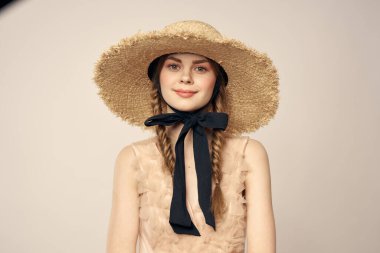 Bej elbiseli, hasır şapkalı, siyah kurdele takmış, manken görünümlü romantik bir kız.