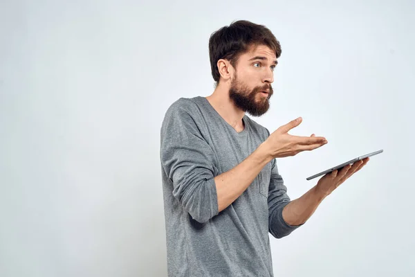 Ein Mann mit einem Tablet in der Hand Internet-Technologie Kommunikation graue Jacke heller Hintergrund — Stockfoto