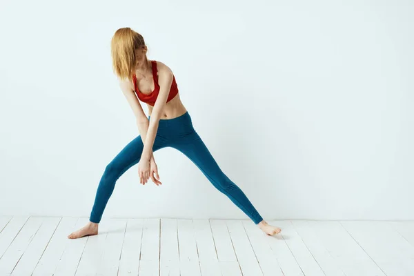 Sportovní žena póza gymnastika rovnováha cvičení lehké pozadí — Stock fotografie