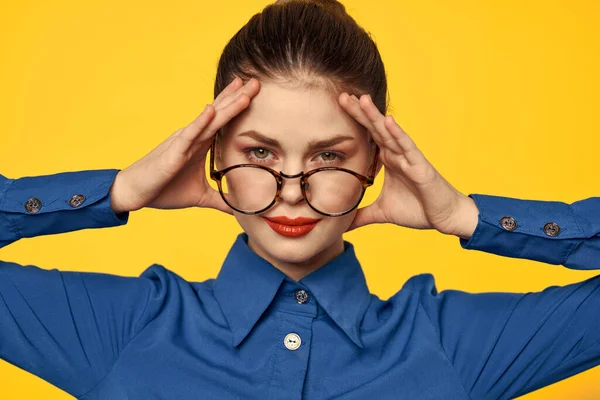 Uma mulher de camisa azul e óculos com maquiagem brilhante no rosto está gesticulando com as mãos Copiar espaço — Fotografia de Stock