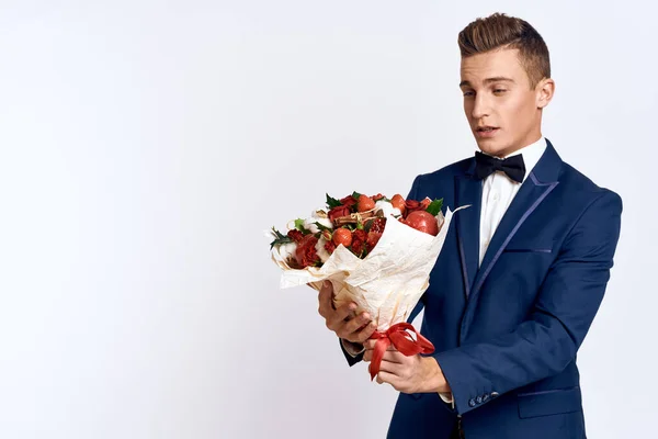 En elegant man i klassisk kostym med fluga håller en bukett blommor i handen — Stockfoto