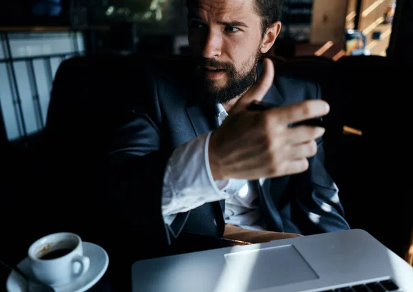 Homme d'affaires en costume dans un café devant un ordinateur portable avec une tasse de boisson officielle — Photo