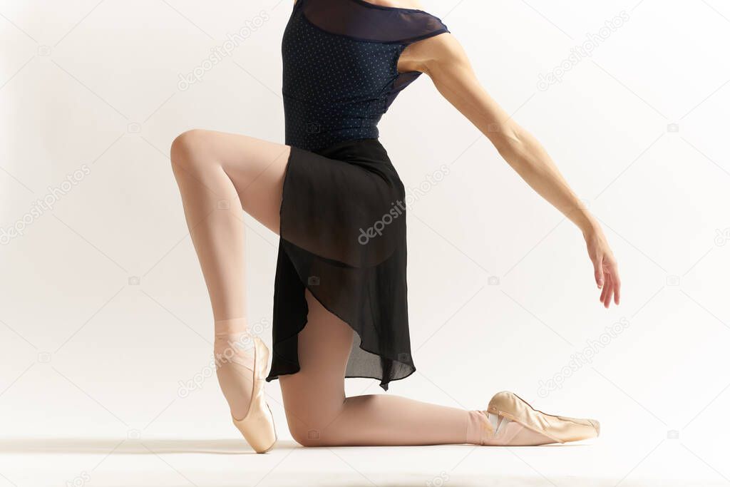 Ballerina in a black dress and in pointe shoes performing a dance on a light background tutu leotard