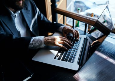 Takım elbiseli bir iş adamı bir kafede ya da dizüstü bilgisayarla oturuyor.