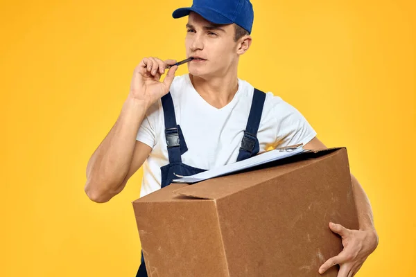 Arbeiter in Uniform mit Box Hand Lieferservice Verladedienst gelben Hintergrund — Stockfoto