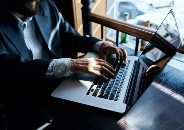 Takım elbiseli bir iş adamı bir kafede ya da dizüstü bilgisayarla oturuyor.