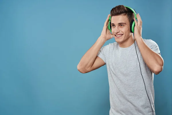 Man in green headphones listens to music entertainment lifestyle white t-shirt blue background