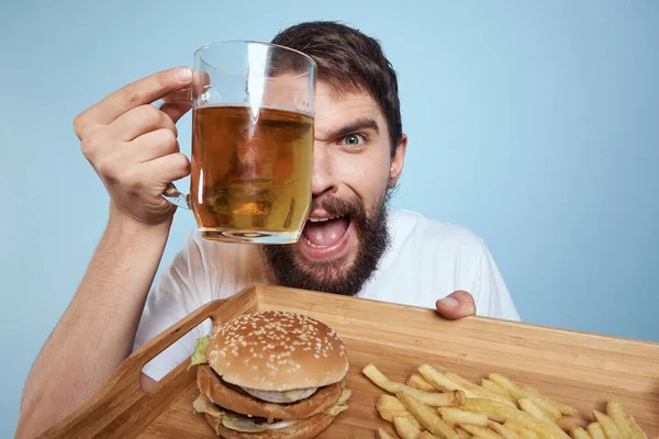 Gai homme bière tasse hamburger frites fast food régime bleu fond close-up — Photo