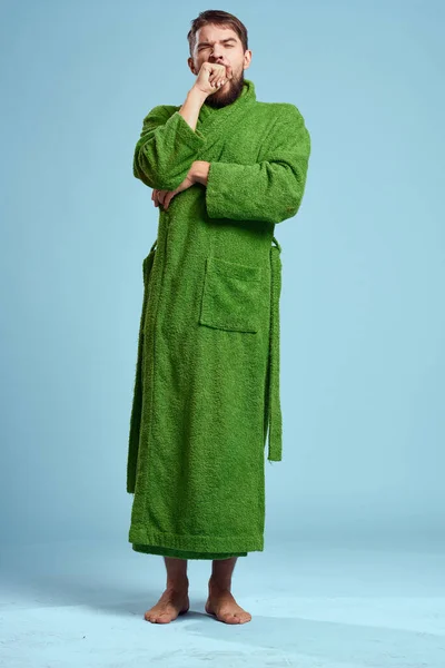 Человек в зеленом халате в полном рост на синем фоне босиком — стоковое фото