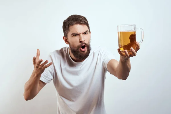 Homem com uma caneca de cerveja em suas mãos e um branco t-shirt luz fundo bigode barba emoções modelo — Fotografia de Stock