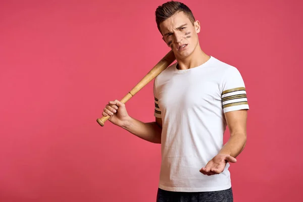 一个手拿着球棒的男人，穿着白色T恤衫，在粉色背景下打棒球 — 图库照片