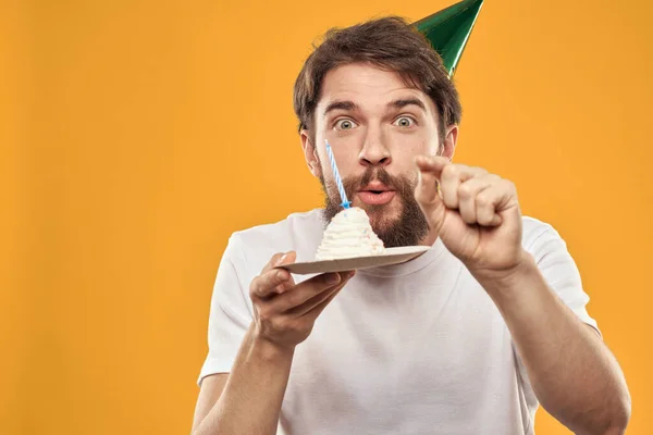 Jóképű férfi szakállal és sapkában ünnepli a születésnapi party sárga háttér — Stock Fotó