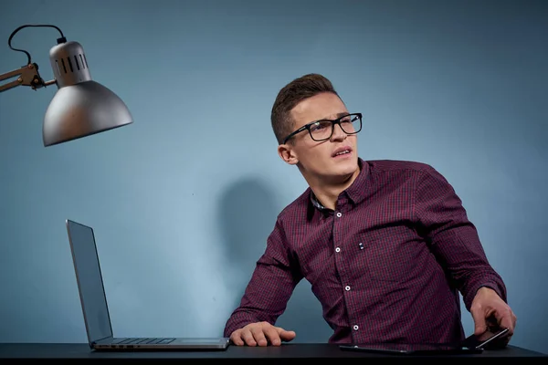 Um homem em uma camisa com um laptop na mesa é um gerente no escritório e um modelo de armário de lâmpadas — Fotografia de Stock