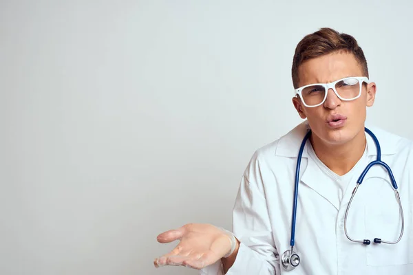 Médico em um vestido médico com um estetoscópio e óculos em um fundo leve corte vista retrato — Fotografia de Stock