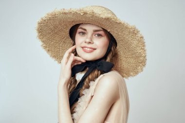 Bej elbiseli, hasır şapkalı, siyah kurdele takmış, manken görünümlü romantik bir kız.