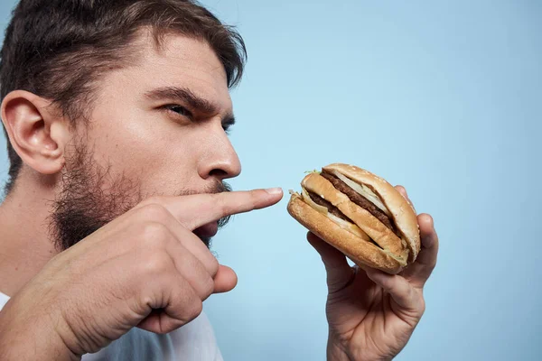 Duygusal adam hamburgeri fast food diyeti yakın plan mavi arka plan — Stok fotoğraf