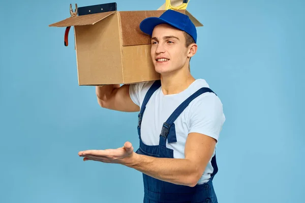 Trabalhador homem em caixa uniforme com ferramentas carregador entrega azul fundo — Fotografia de Stock