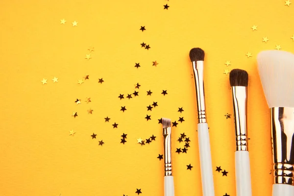 Cepillos de maquillaje en diferentes tamaños sobre un fondo amarillo y aspecto recortado brillo —  Fotos de Stock
