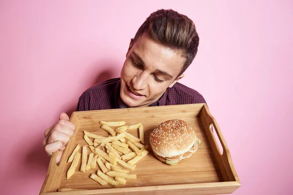 Mann mit Fast Food essen Hamburger Pommes rosa Hintergrund — Stockfoto