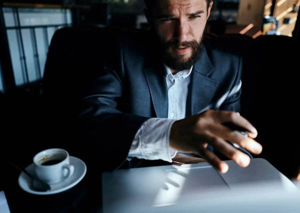 Homme d'affaires en costume dans un café devant un ordinateur portable avec une tasse de boisson officielle — Photo
