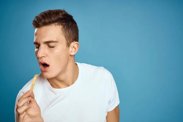 Uomo con patatine fritte in piatto di cartone calorie fast food sfondo blu teen modello ritagliato vista — Foto Stock