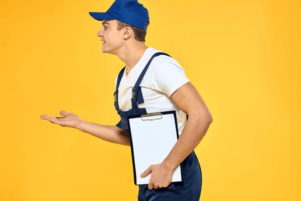 Mann in Arbeitsuniform dokumentiert Übertragung von Dienstleistungen Lieferservice gelben Hintergrund — Stockfoto