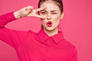 Pembe tişörtlü çekici bir kız parlak makyajlı kırmızı dudaklar ellerle işaret ediyor Boşluğu kopyala