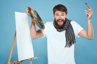 Erkek sanatçı palet fırçası resim sehpası mavi arka plan