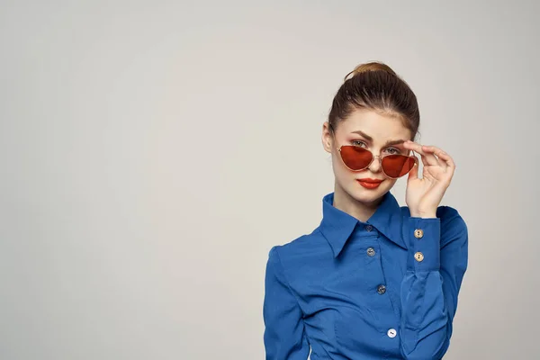 Retrato de uma mulher em óculos de sol e uma camisa azul em um fundo claro vista recortada de Model Copy Space — Fotografia de Stock