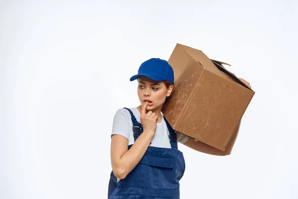 Kvinna arbetar uniform låda i händerna packning service ljus bakgrund — Stockfoto