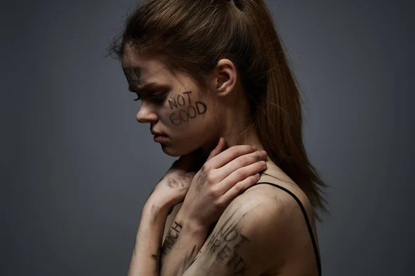 Donna sconvolta con scrittura offensiva sul suo corpo su sfondo grigio toccarsi con le mani ritagliato vista — Foto Stock
