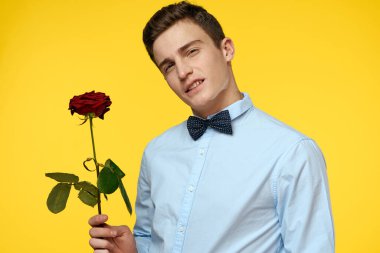 Sarı arka planda kırmızı gül ve açık gömlek papyonlu bir beyefendinin portresi.