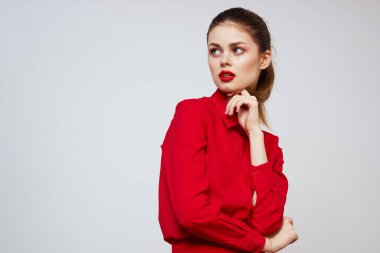Kırmızı dudaklı güzel bir kız ve arka planda açık renk jestleri olan bir gömlek.