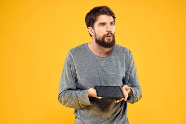 Følelsesmessig mann med nettbrett i hendene Internett-enhet, gul bakgrunn – stockfoto