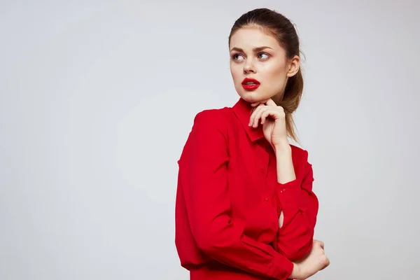 A beautiful girl with red lips and a shirt on a light background gestures with her hands — Stock Photo, Image