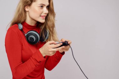 Kulaklık kontrolörü olan bir kadın konsol oyunu eğlence amaçlı kırmızı ceketli yaşam tarzı hafif arka plan