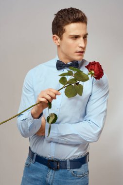 Kırmızı gül ve açık renk pantolon giyen romantik bir adam.