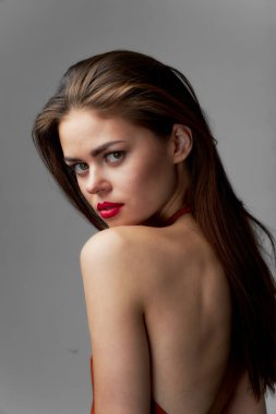 Güzel bir kadın. Çıplak omuzlar. Gri arka planda kırmızı ruj. 